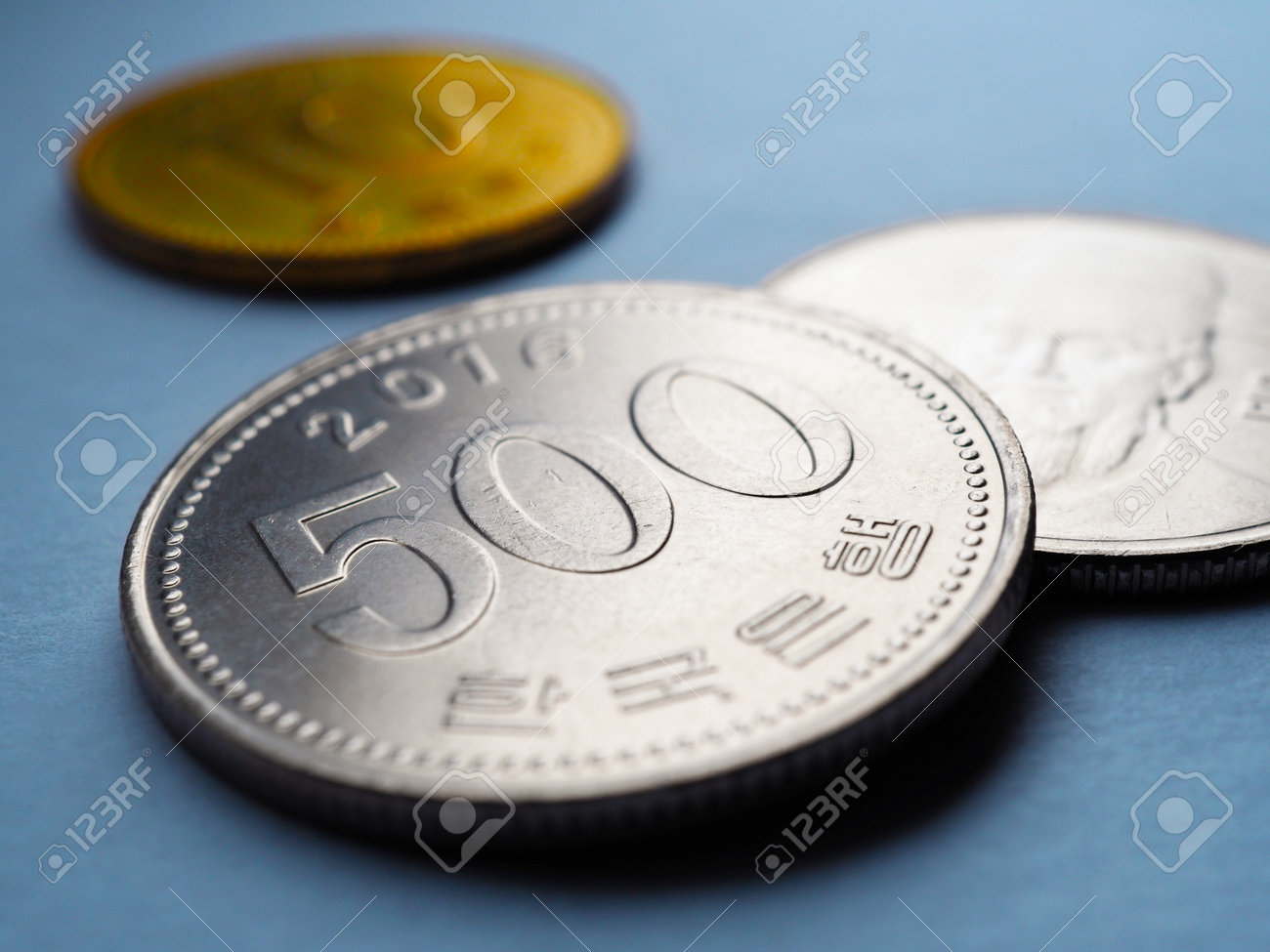 翻訳:韓国銀行。韓国の硬貨は青い紙の表面に横たわっています。500ウォン硬貨の接写。経済、金融、銀行に関するイラスト。韓国でのお金とビジネス。マクロの写真素材・画像素材  Image 198079699