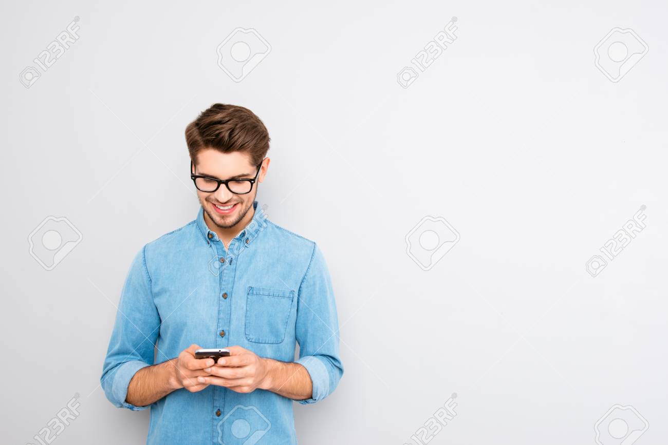 Happy man in glasses typing sms on gray background - 61229831 Happy man in glasses typing sms on gray background - 61229831