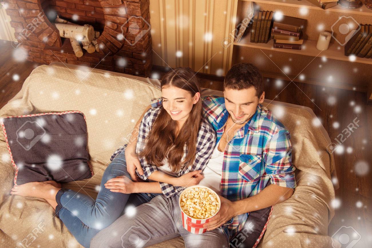 クリスマスの夜にポップコーン テレビを見て魅力的なカップル の写真