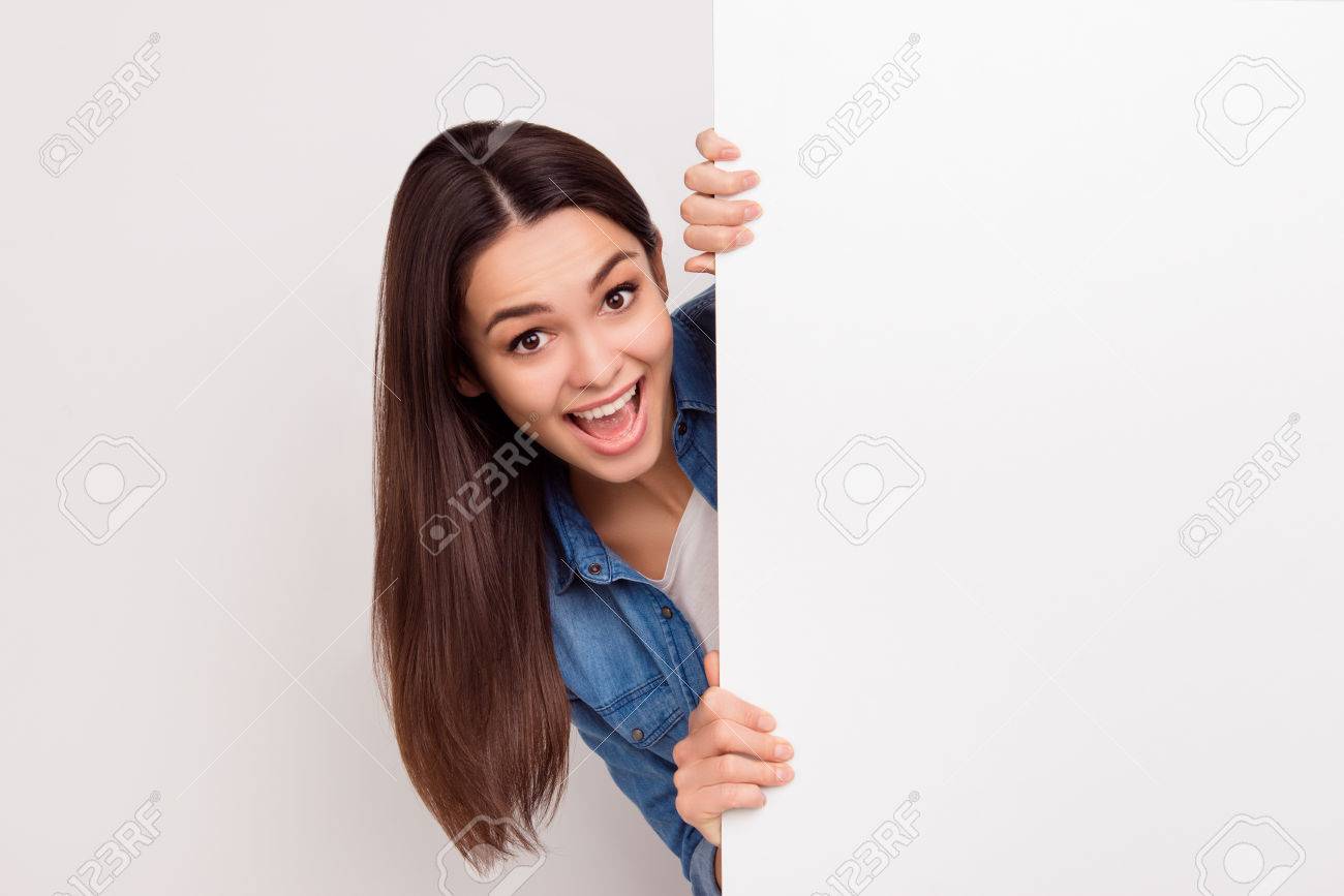 happy amazed young girl is popping out from white blank banner stock