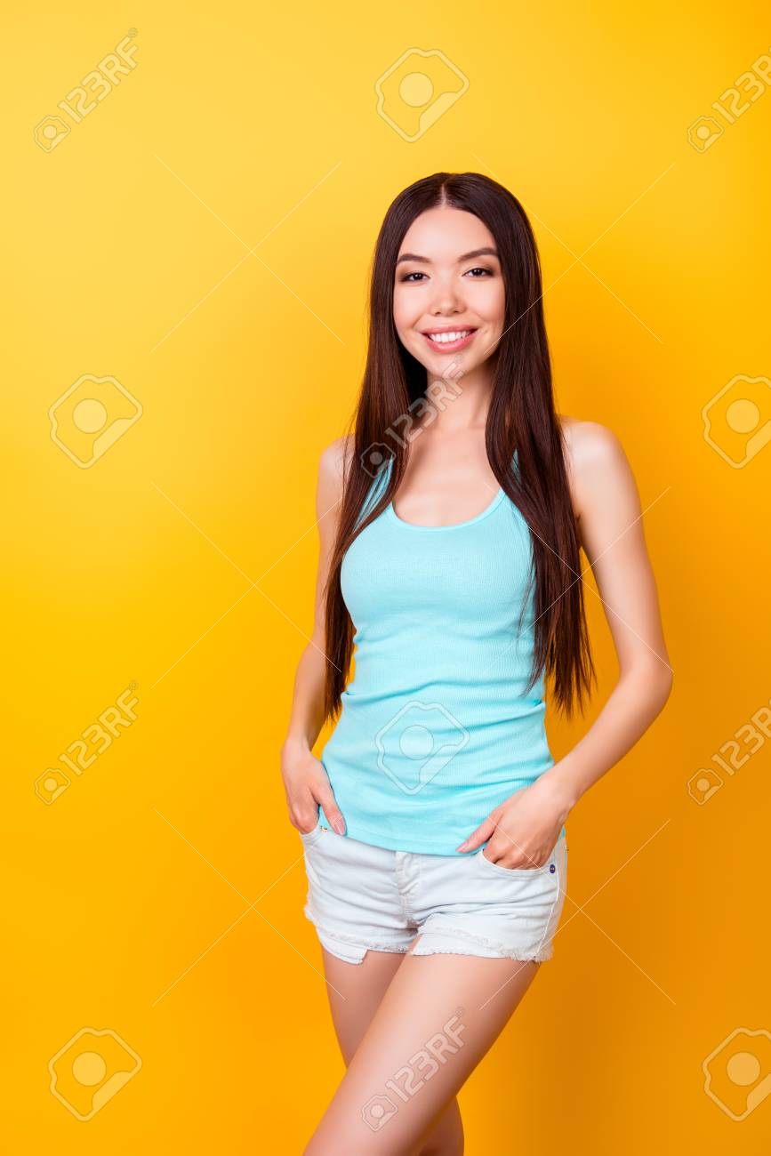 夏の衣装で若いかわいい韓国人女性が明るい黄色の背景にポーズで立っています 彼女はとてもやせて魅力的で 長い素敵な髪をしています の写真素材 画像素材 Image