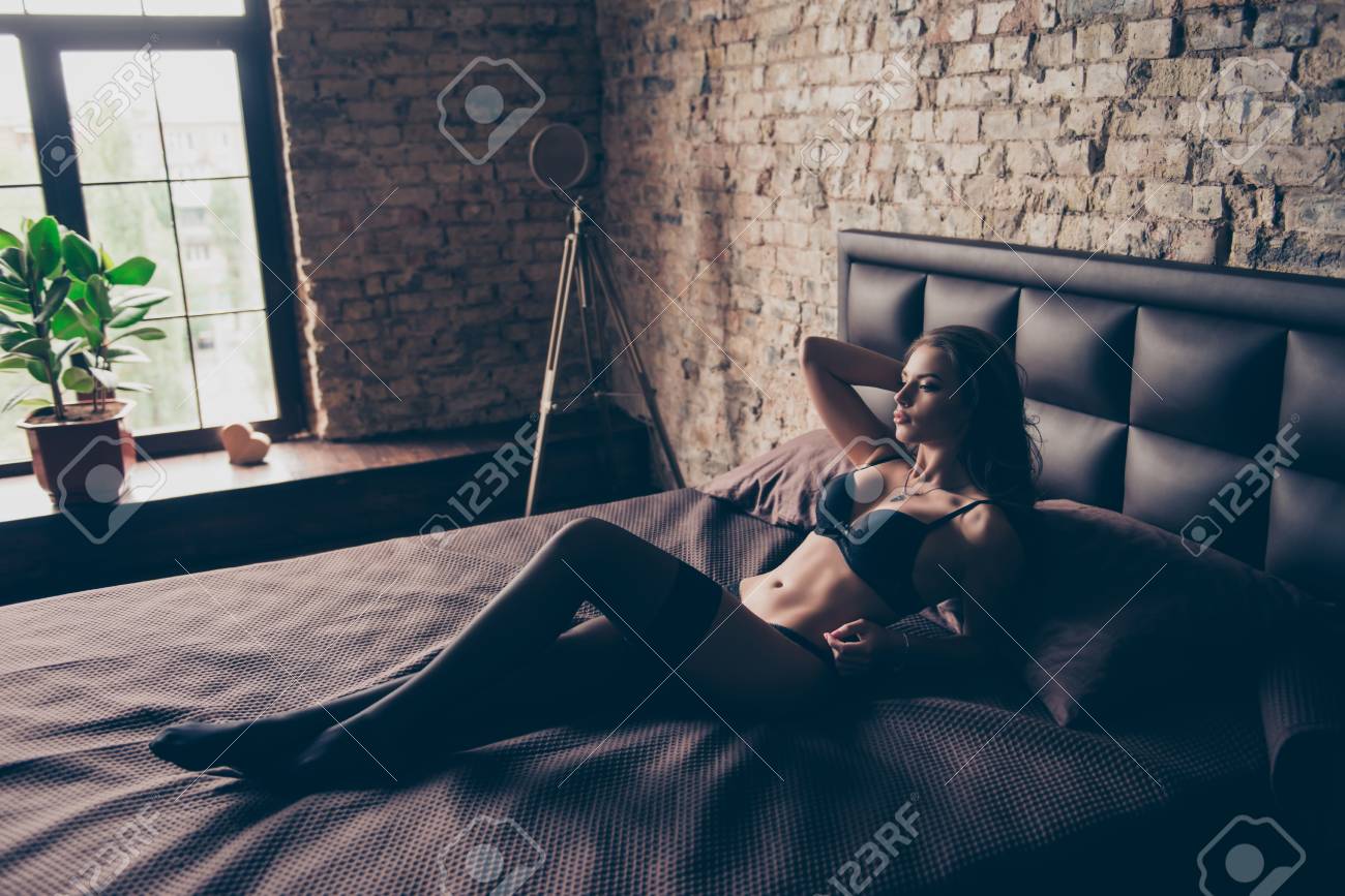 Stunning Young Sexy Brunette Is Lying Down On The Bed In Dark Loft Room photo