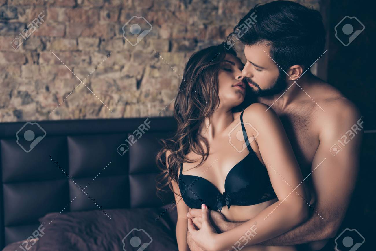 Beautiful Half Naked Brunet Young Couple Is Embracing In The Bed Room,  About To Have Sex, So Tender, Romantic, Tempting, Sensual. True Love And  Feelings, Gentle Touch And Caress Stock Photo, Picture