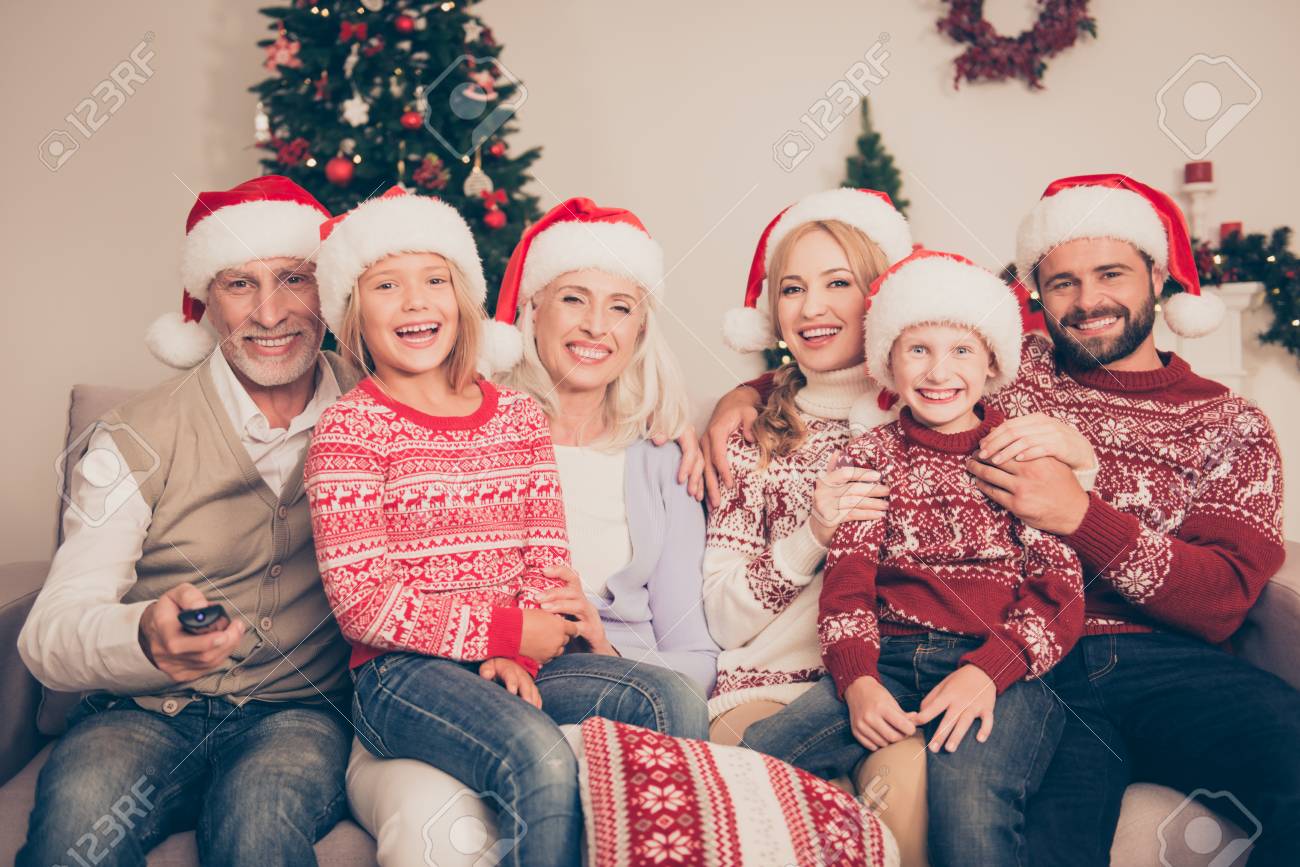 Group of cheerful relatives embrace bonding on couch, married couples, excited siblings, grandad, granny, in knitted cute traditional x mas costumes, pine firtree, home, movie, laugh - 88129908 Group of cheerful relatives embrace bonding on couch, married couples, excited siblings, grandad, granny, in knitted cute traditional x mas costumes, pine firtree, home, movie, laugh - 88129908