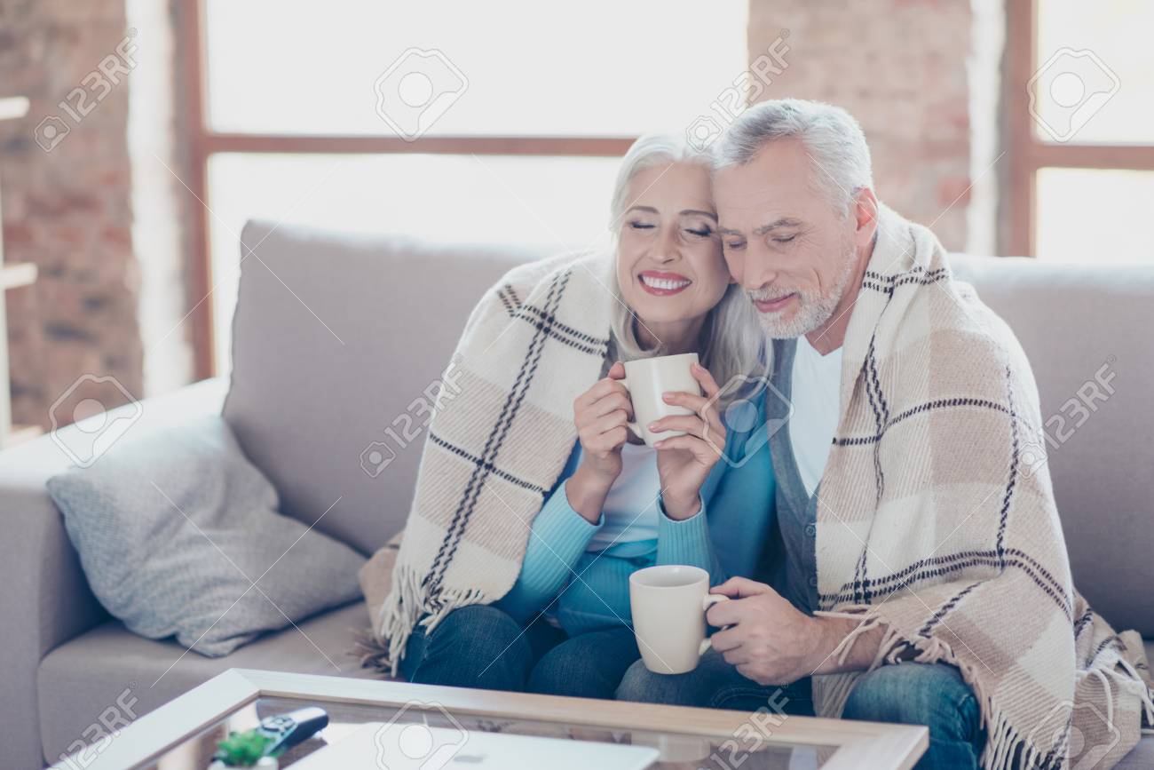 It is almost winter, so cold outside, but so sweet time we spend together! Happy cheerful peaceful couple of pensioners are resting, relaxing, hugging, drinking tea with closed eyes at the weekend - 90964346 It is almost winter, so cold outside, but so sweet time we spend together! Happy cheerful peaceful couple of pensioners are resting, relaxing, hugging, drinking tea with closed eyes at the weekend - 90964346