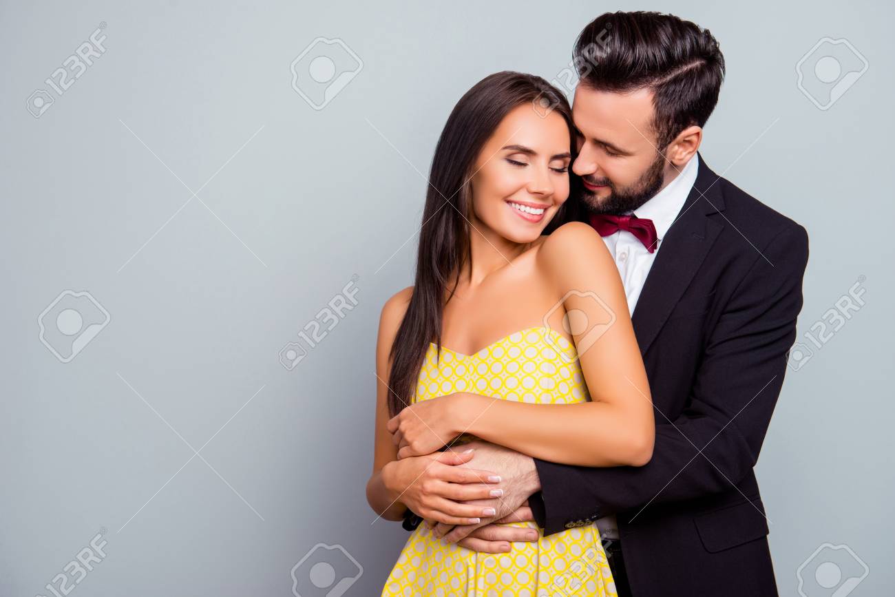 Photo Of Beautiful, Cheerful, Positive, Cute, Sensual, Tender Couple  Enjoying Hugs With Each Other Having Eyes Close Over Grey Background With  Copy Space, Gentle Husband's Hands Touch His Wife Stock Photo, Picture, image size:1300x867