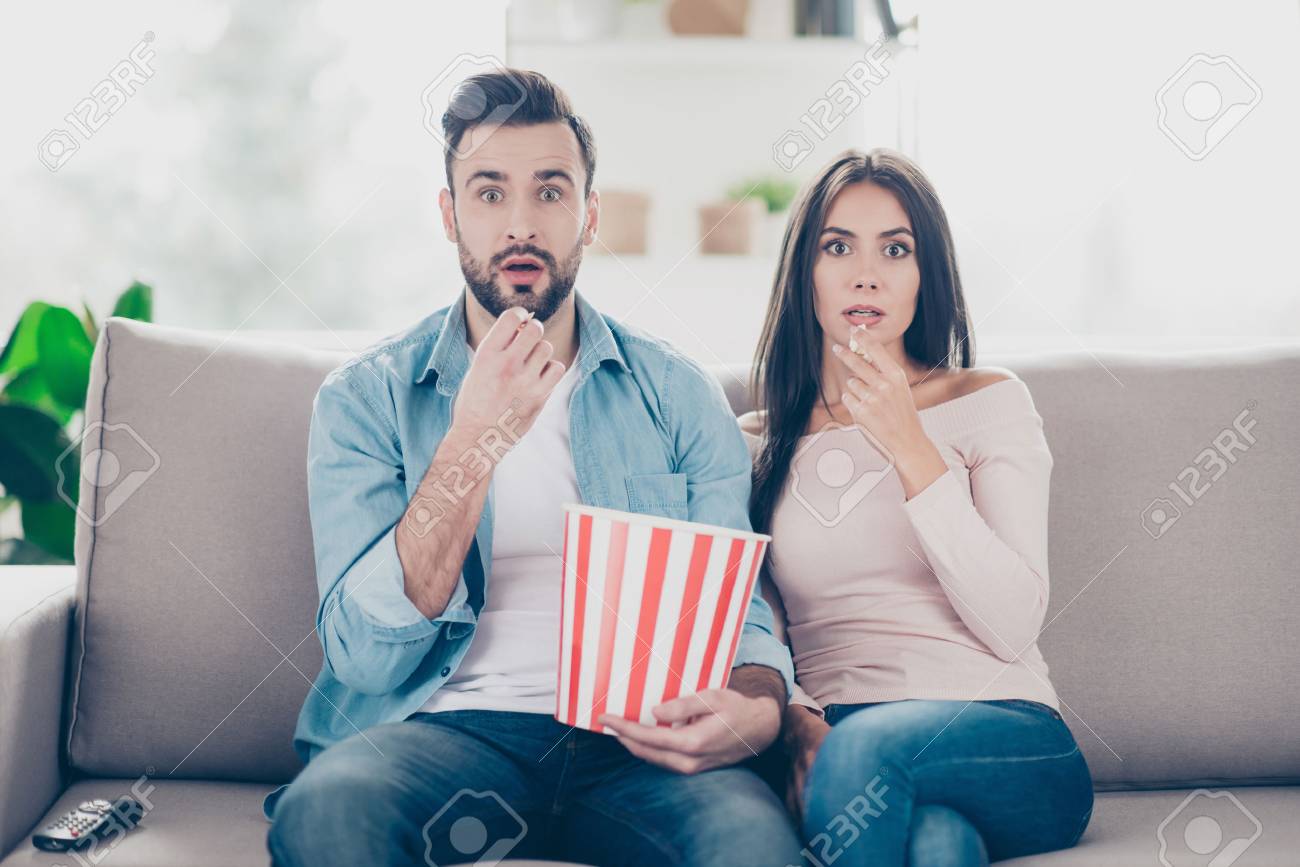 Unexpected turn of events in a film! Two charming beautiful funny man with bristle clothed in jeans denim outfit and attractive dressed in sweater and jeans woman are pop-eyes surprised watching tv - 93377134 Unexpected turn of events in a film! Two charming beautiful funny man with bristle clothed in jeans denim outfit and attractive dressed in sweater and jeans woman are pop-eyes surprised watching tv - 93377134
