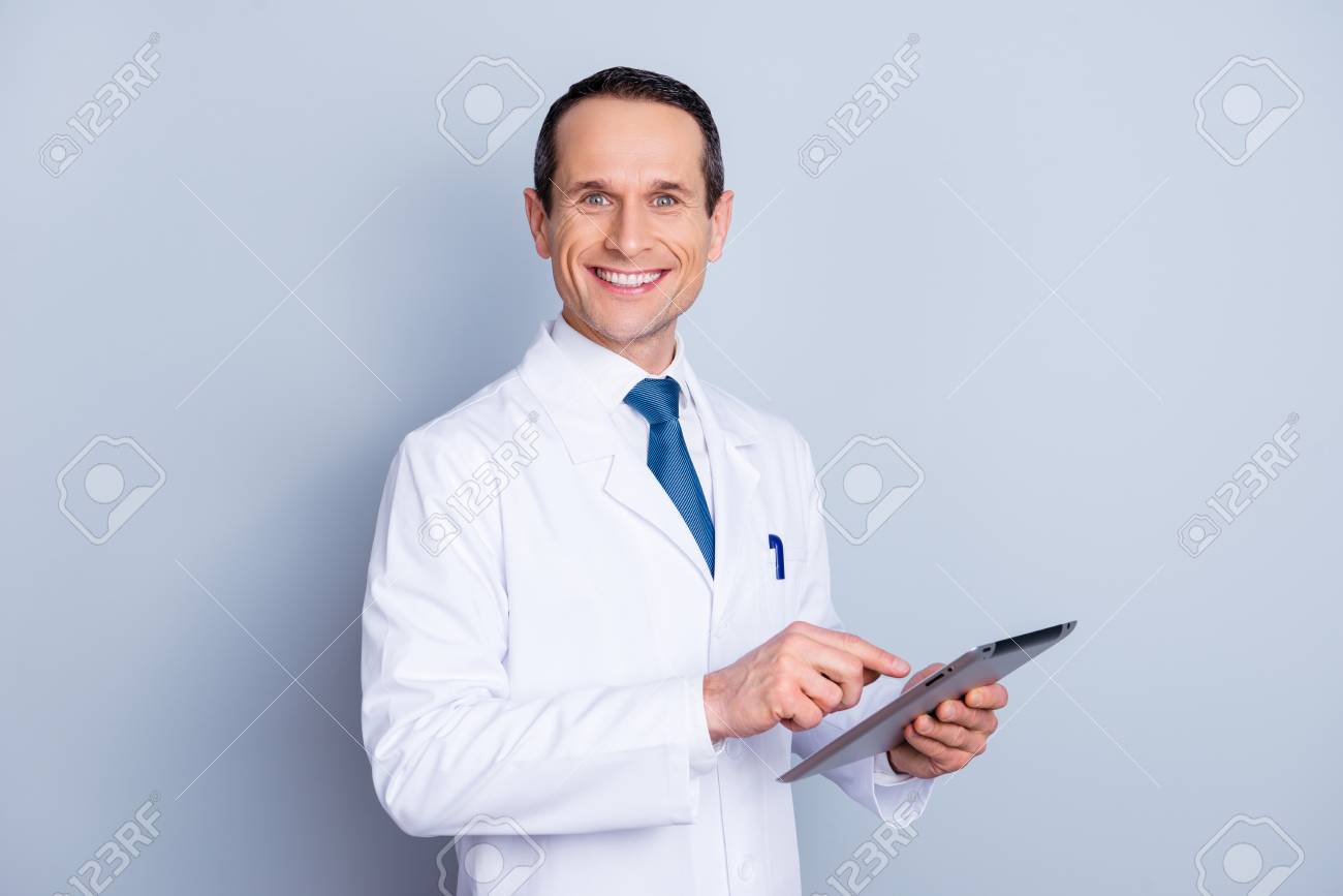 Portrait of cheerful glad gifted smart with toothy smile doctor using modern pad at work isolated on gray background copy-space - 97864772 Portrait of cheerful glad gifted smart with toothy smile doctor using modern pad at work isolated on gray background copy-space - 97864772