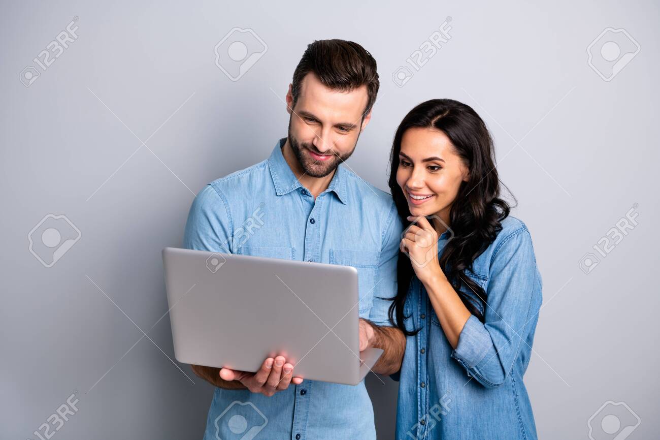 Portrait of charming inspired students using electronic devices watching videos browsing sites social networks isolated dressed in blue denim clothing on gray background - 119455104 Portrait of charming inspired students using electronic devices watching videos browsing sites social networks isolated dressed in blue denim clothing on gray background - 119455104
