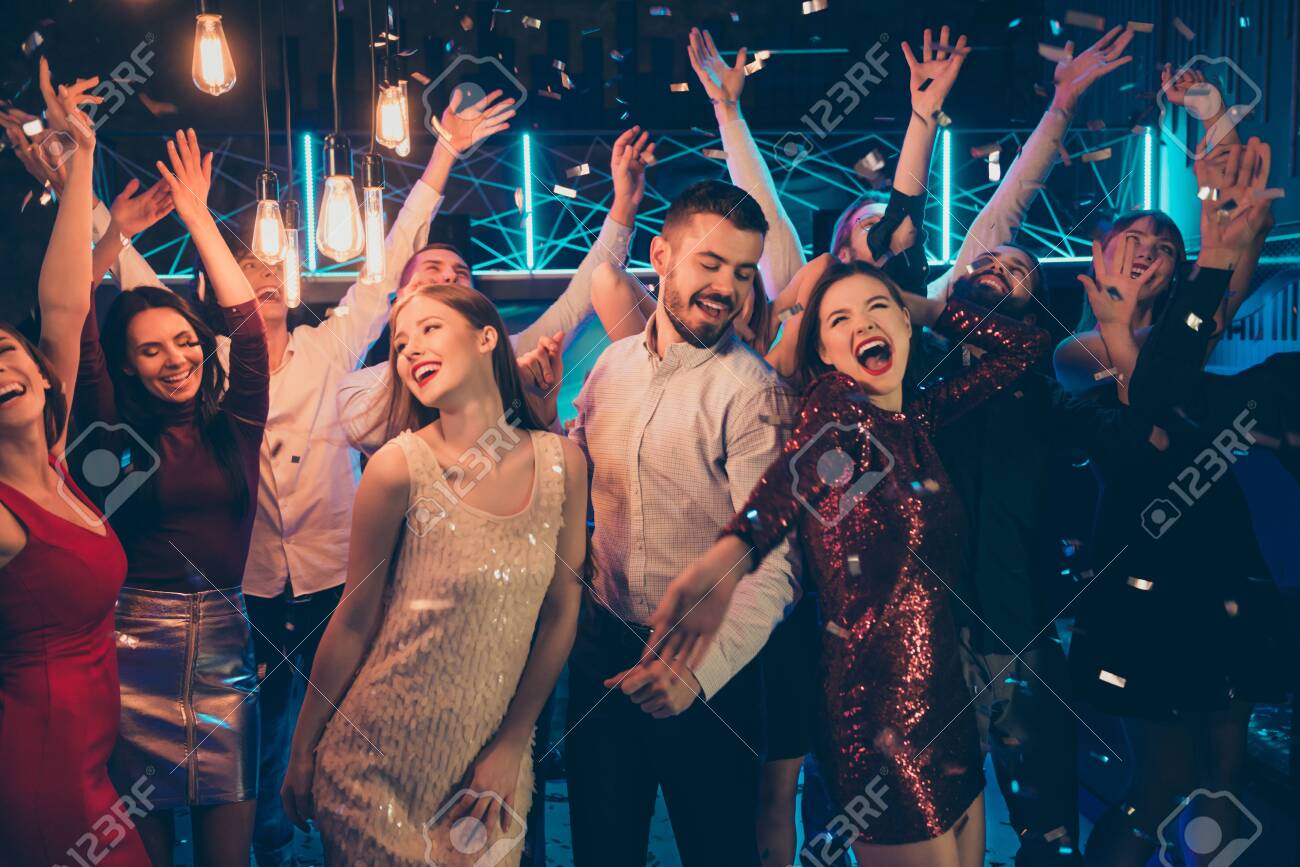 Photo of dancing people dressed in formalwear rejoicing good free time together with macho surrounded by girls hanging out between them in falling confetti - 133115901 Photo of dancing people dressed in formalwear rejoicing good free time together with macho surrounded by girls hanging out between them in falling confetti - 133115901