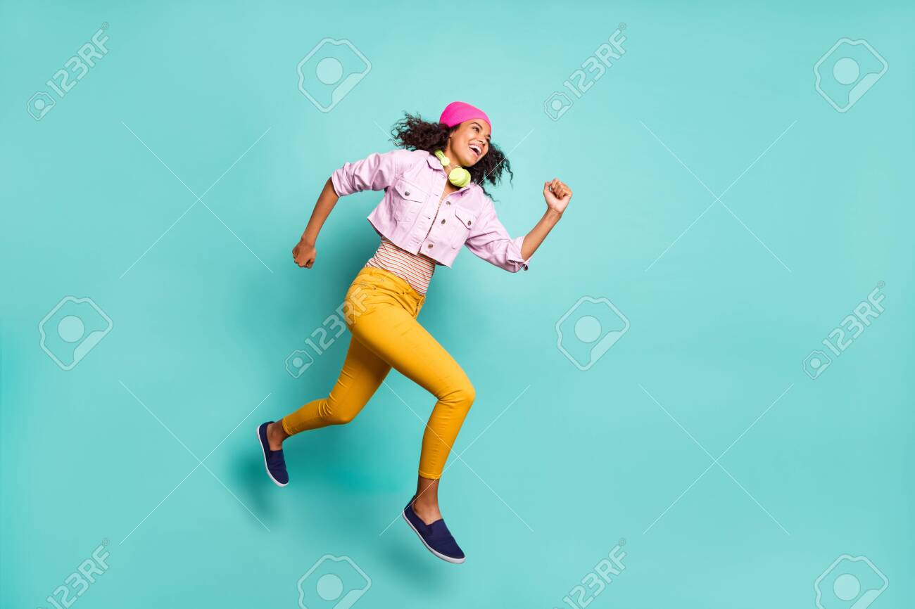 Turned full length body size photo of casual positive running jumping girl aspiring for discounted goods wearing yellow pants trousers pink jacket striped t-shirt isolated teal color background vivid - 133956688 Turned full length body size photo of casual positive running jumping girl aspiring for discounted goods wearing yellow pants trousers pink jacket striped t-shirt isolated teal color background vivid - 133956688