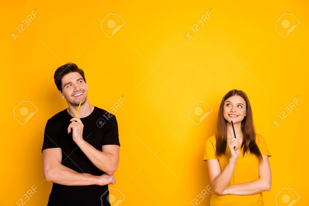 Photo of cheerful positive cute nice charming pretty couple holding pens wearing black t-shirt smiling toothily looking into empty space a fit of thoughts isolated over bright shiny color background - 134708107 Photo of cheerful positive cute nice charming pretty couple holding pens wearing black t-shirt smiling toothily looking into empty space a fit of thoughts isolated over bright shiny color background - 134708107