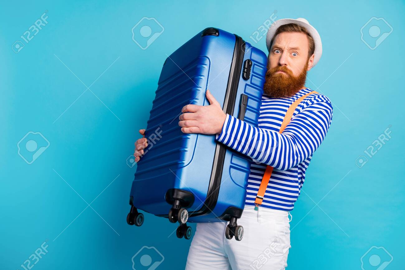 Portrait of serious man bad moody hold heavy luggage he prepare for voyage weekend tourism resort airport wear good look vest isolated over blue color background - 138776100 Portrait of serious man bad moody hold heavy luggage he prepare for voyage weekend tourism resort airport wear good look vest isolated over blue color background - 138776100