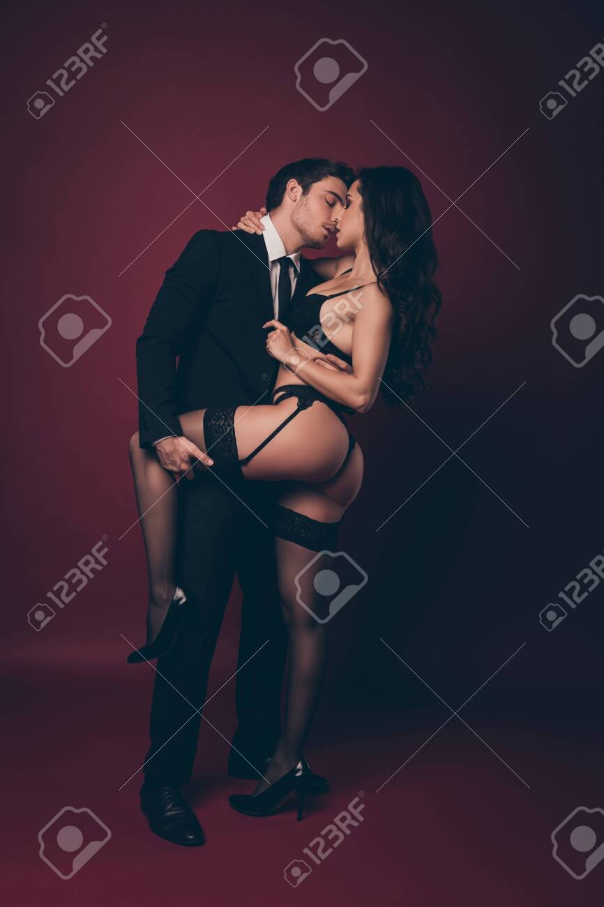 Full Size Vertical Photo Of Horny Two People Husband Return Home Work Nude Hot Shapes Bum Black Underwear Wife Meets Macho Undress His Office Suit Isolated Burgundy Color Background Stock Photo, Picture