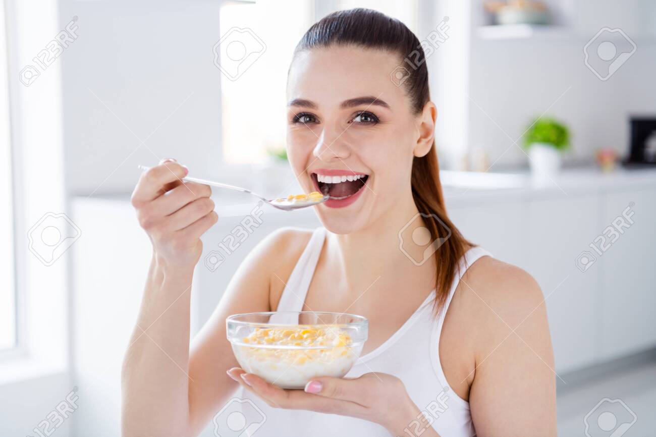 Closeup photo of pretty housewife lady sit morning kitchen have breakfast eat cereal corn flakes milk stay home distance remote work good mood quarantine time indoors - 148491072 Closeup photo of pretty housewife lady sit morning kitchen have breakfast eat cereal corn flakes milk stay home distance remote work good mood quarantine time indoors - 148491072