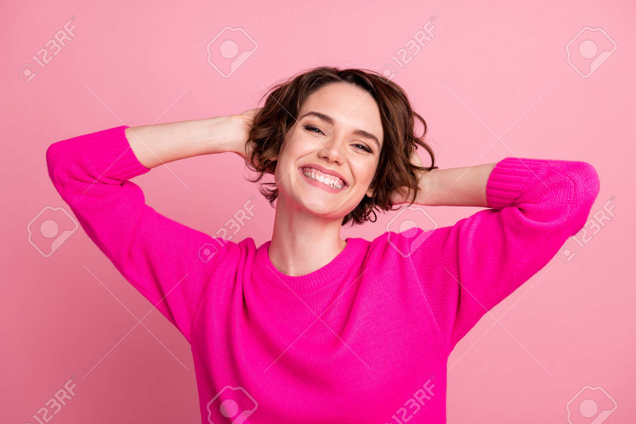 Closeup photo of pretty funny lady hold hands behind head dreamer toothy smiling excited good mood wear casual sweater pullover isolated pink pastel color background - 154193356 Closeup photo of pretty funny lady hold hands behind head dreamer toothy smiling excited good mood wear casual sweater pullover isolated pink pastel color background - 154193356