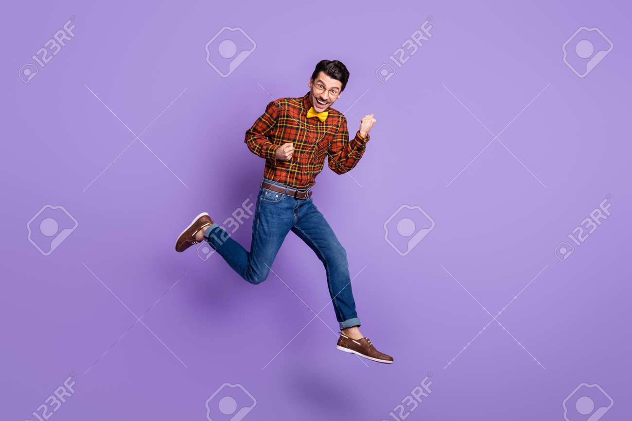 Full size photo of young handsome cheerful smiling positive man jumping in victory isolated on violet color background - 167187438 Full size photo of young handsome cheerful smiling positive man jumping in victory isolated on violet color background - 167187438