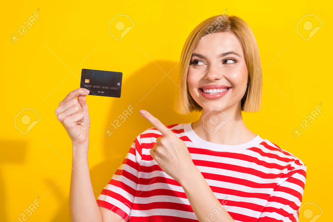 鮮やかな黄色の背景にスタイリッシュな服を着たポジティブで素敵な金持ちの女の子の写真は、カードで支払うことをお勧めしますの写真素材・画像素材 Image  211449524