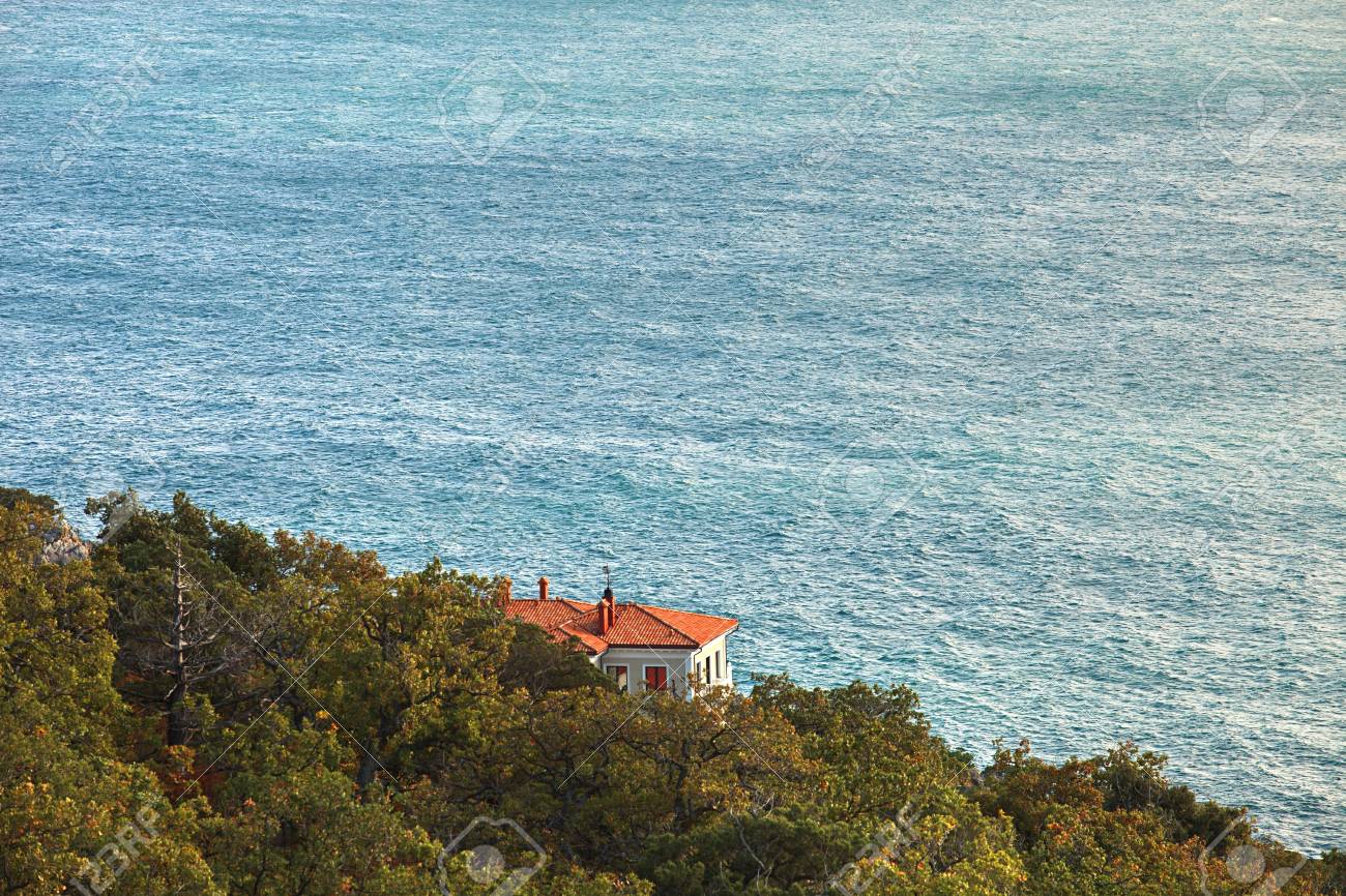 海の背景に丘の中腹に赤い屋根のコテージ 海や海の静かな場所 明るい晴れた日の穏やかな海 森の中のコテージ 森の中や公園の家 丘の中腹に戸建住宅 家と海の平面図です Decidu の写真素材 画像素材 Image