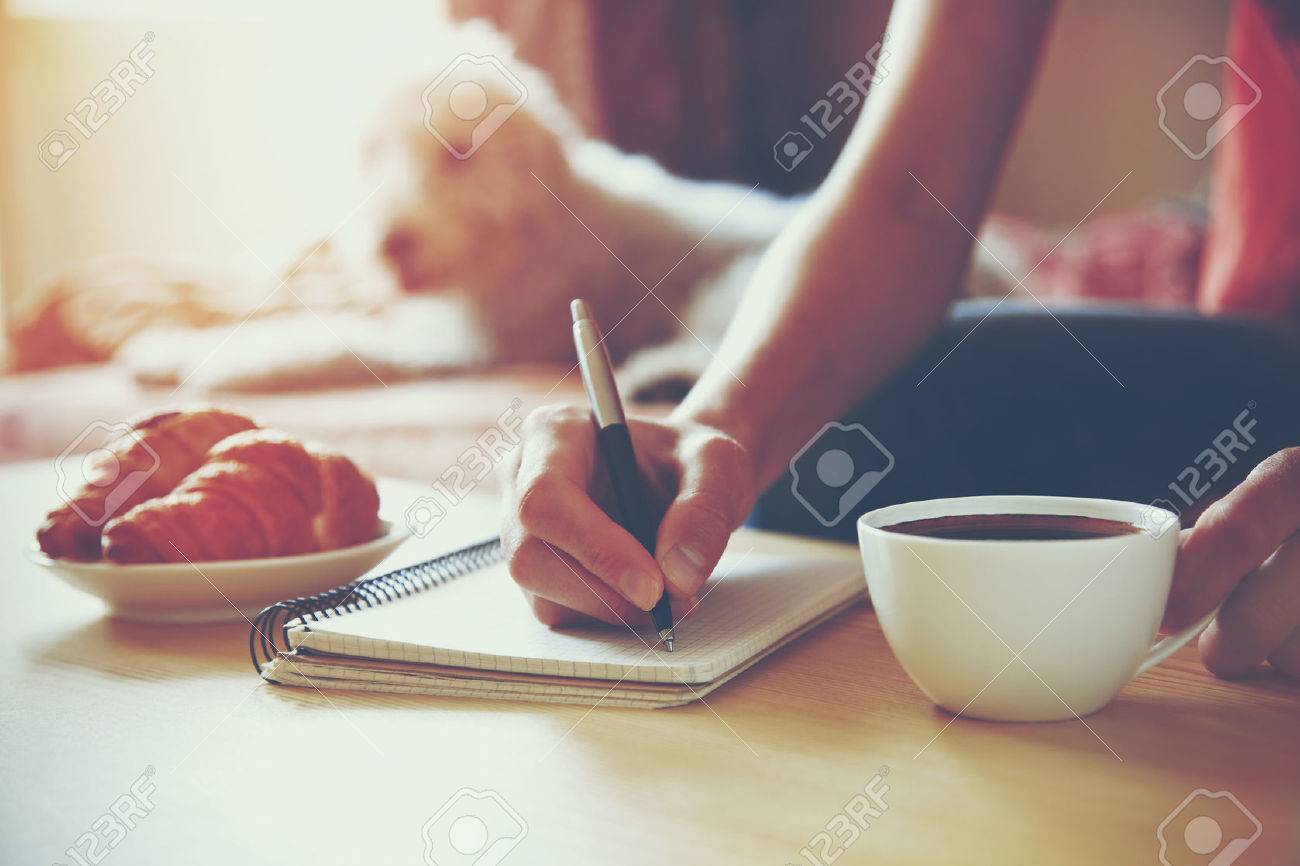 female hands with pen writing on notebook with morning coffee and croissant - 46650863 female hands with pen writing on notebook with morning coffee and croissant - 46650863