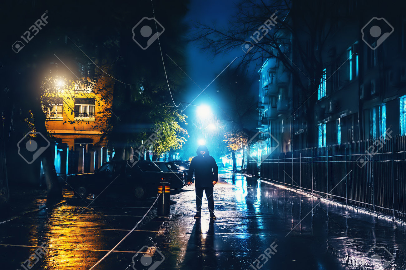 Silhueta de estranho sozinho no capô na rua da cidade à noite na chuva. assassino assustador ou perseguidor, criminoso fica na sombra com luzes urbanas refletidas em poças. thriller horror atmosfera misteriosa. - 160953548 Silhueta de estranho sozinho no capô na rua da cidade à noite na chuva. assassino assustador ou perseguidor, criminoso fica na sombra com luzes urbanas refletidas em poças. thriller horror atmosfera misteriosa. - 160953548