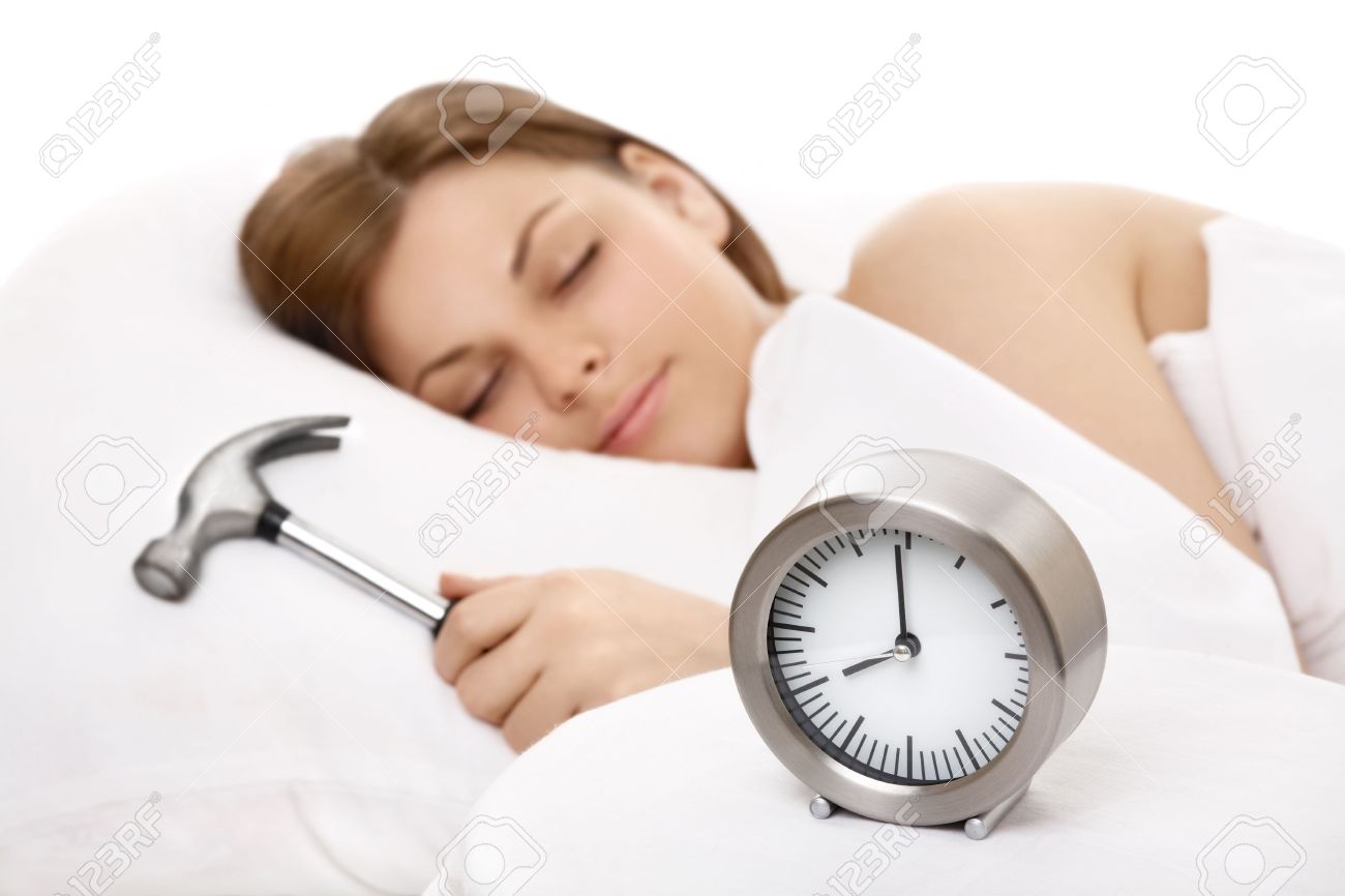 alarm clock against the sleeping girl with a hammer in a hand stock