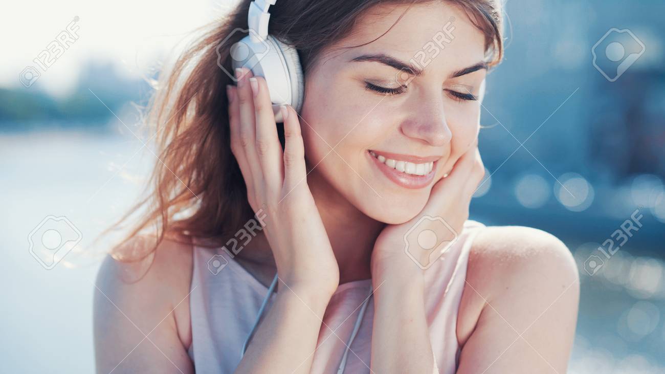 Smiling Girl Listen To Music With Headphones Outdoors Stock Photo, Picture  and Royalty Free Image. Image 98203682., image size:1300x731
