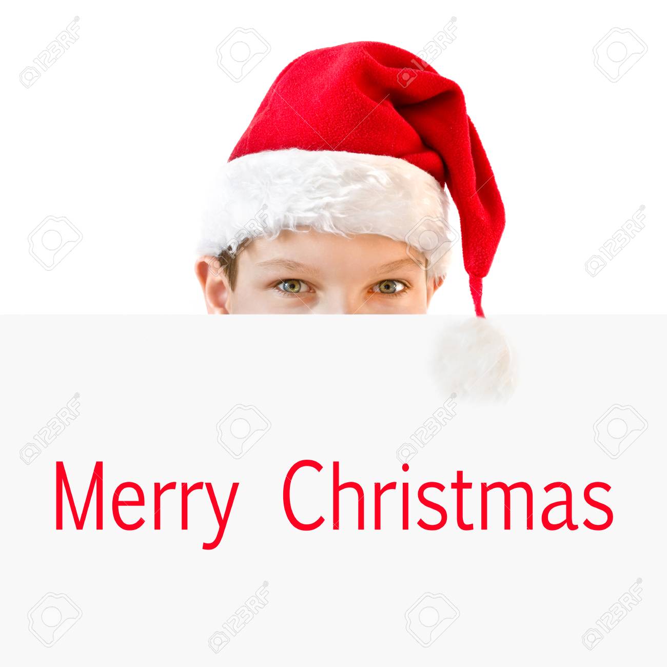 young boy in red santa hat hiding behind a paper merry christmas