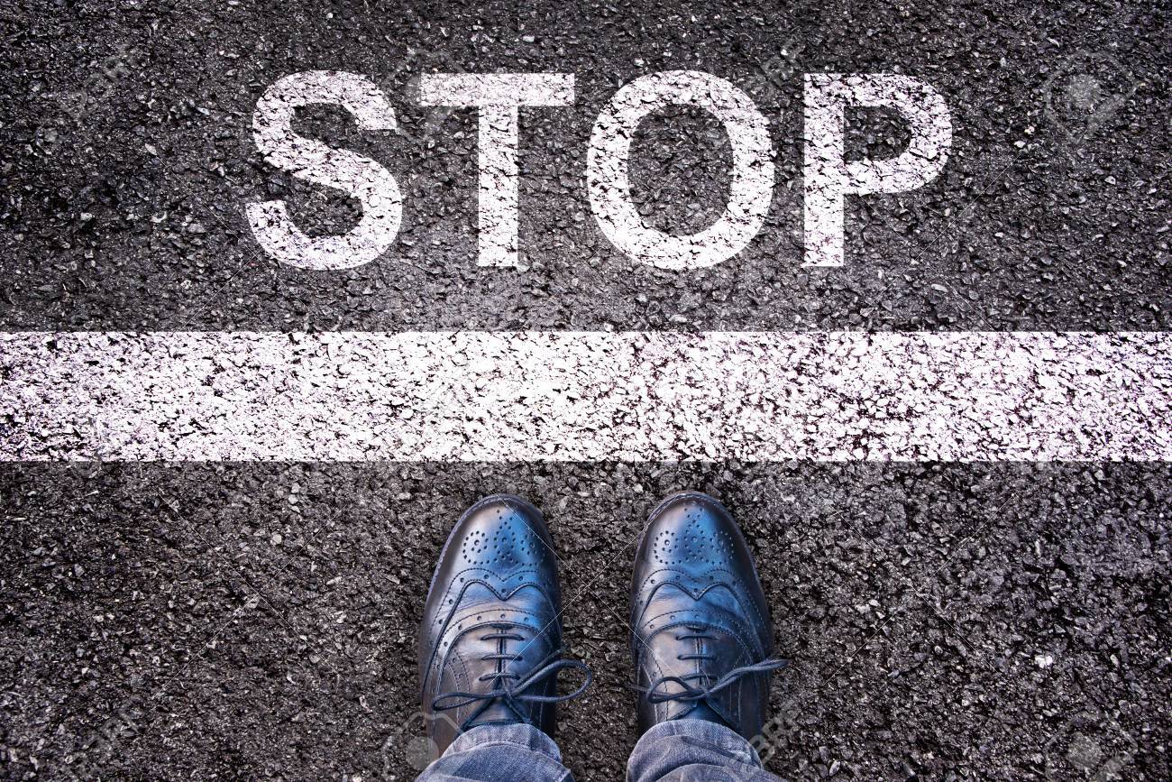 Word Stop written on an asphalt road with legs and shoes - 51573685 Word Stop written on an asphalt road with legs and shoes - 51573685