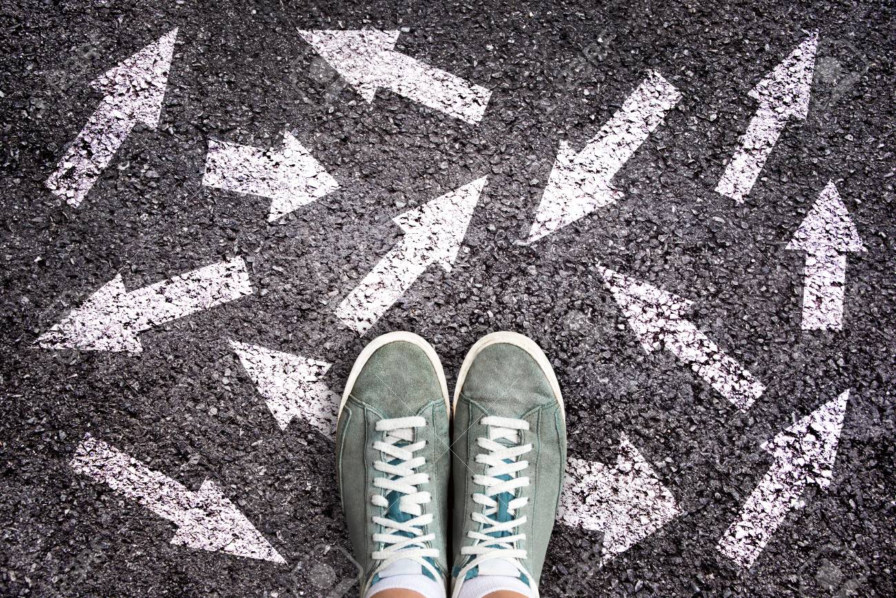 Sneaker shoes and arrows pointing in different directions on asphalt ground, choice concept - 119776553 Sneaker shoes and arrows pointing in different directions on asphalt ground, choice concept - 119776553