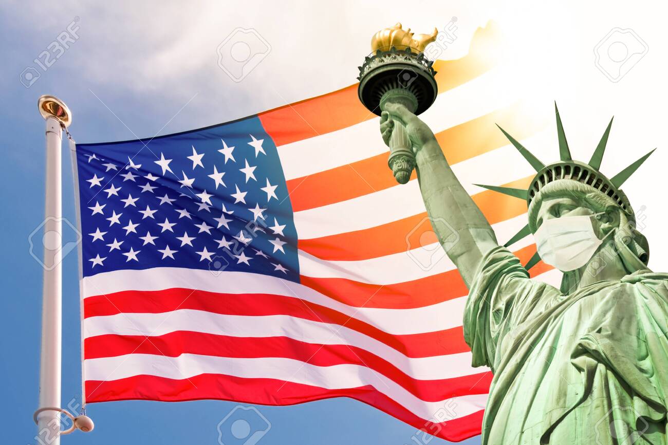 Statue of Liberty wearing a surgical mask, US american flag background. New coronavirus, covid-19 in New York and USA epidemic crisis concept - 143427967 Statue of Liberty wearing a surgical mask, US american flag background. New coronavirus, covid-19 in New York and USA epidemic crisis concept - 143427967