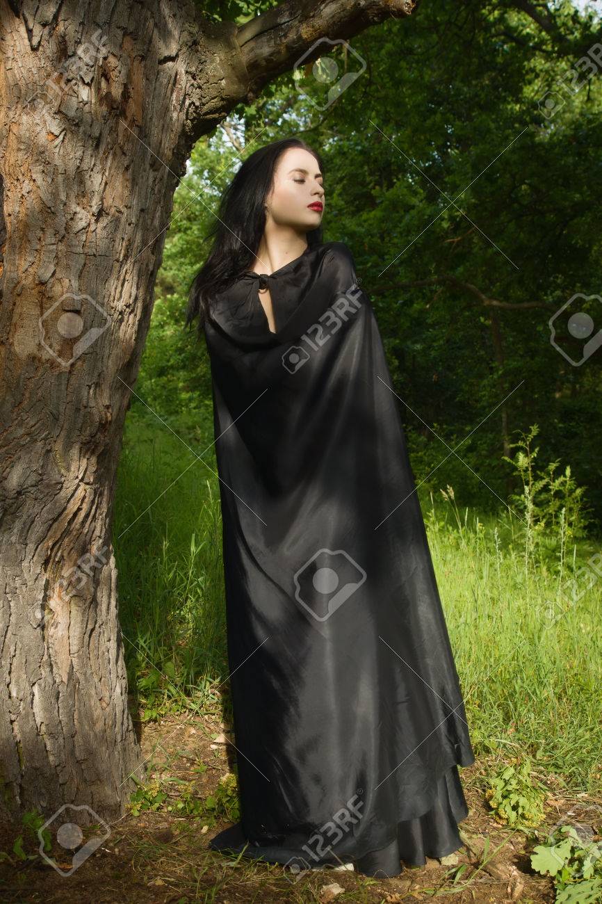 黒のドレス、魔法の森で黒マントで美しいブルネットの女性。ゴシック