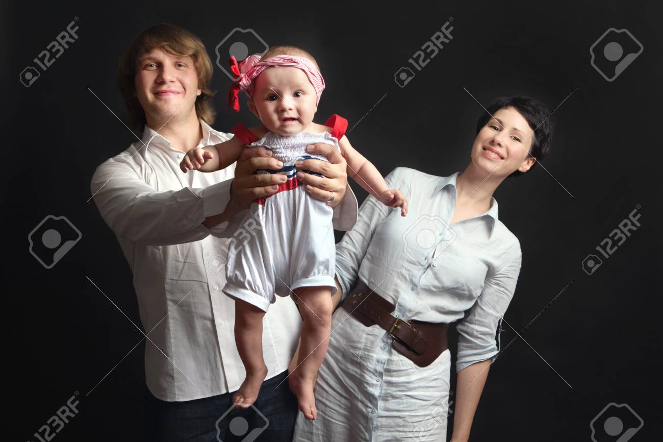 ハッピーと若い親母と父 黒の背景に生後 7 ヶ月の赤ちゃんと女の子の再生を笑顔の肖像画 幸せな家族の概念 の写真素材 画像素材 Image