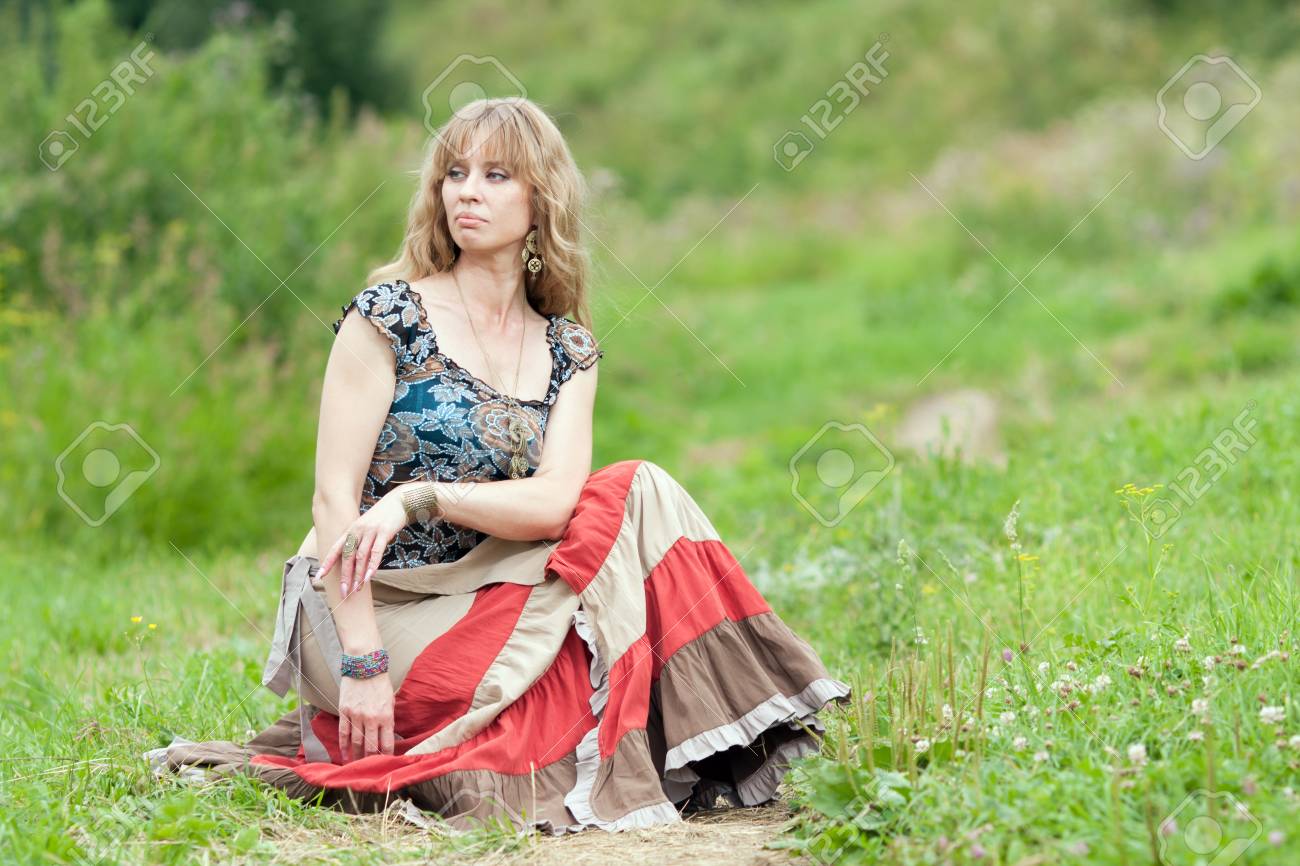 スカートのヒッピーの女性は草の上に座っています の写真素材 画像素材 Image