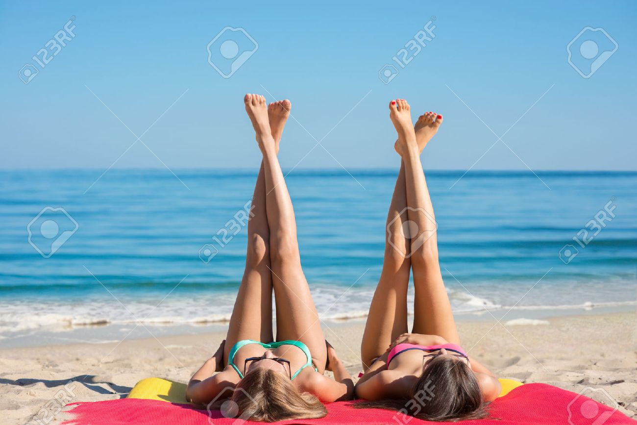 海で日光浴の女の子 ガール フレンドは ビーチでの残りを持っています ビーチで若い女の子の足が長い 休暇でリラックスします 性的な女の子が海岸で横になっています の写真素材 画像素材 Image