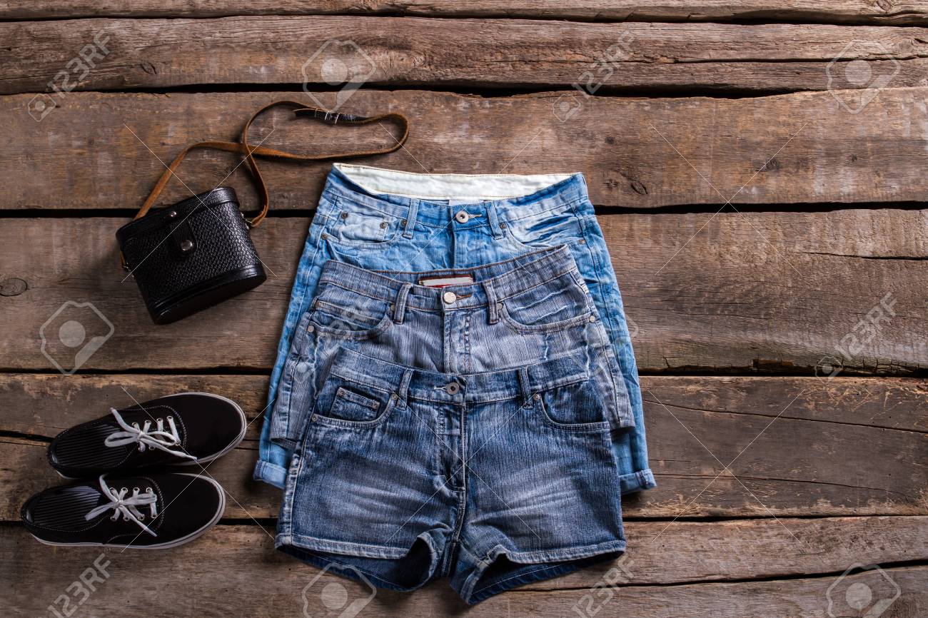 Pantalones Cortos De Mezclilla Diferentes Longitud De Señoras. Diferentes Pantalones Cortos En Mesa De Edad. Cortocircuitos Femeninos Clásicos Con Los Keds. Zapatos Negros Y Pantalones Cortos De La Fotos,