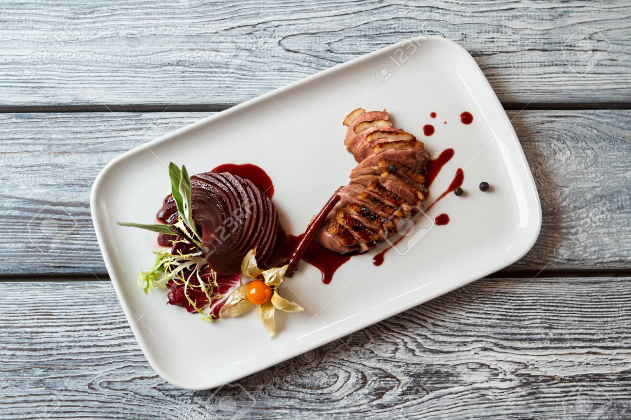 Assiette avec de la viande cuite. Tranches de viande avec décoration. Magret de canard avec une sauce sucrée. Délicatesse de la cuisine européenne. Assiette avec de la viande cuite. Tranches de viande avec décoration. Magret de canard avec une sauce sucrée. Délicatesse de la cuisine européenne.