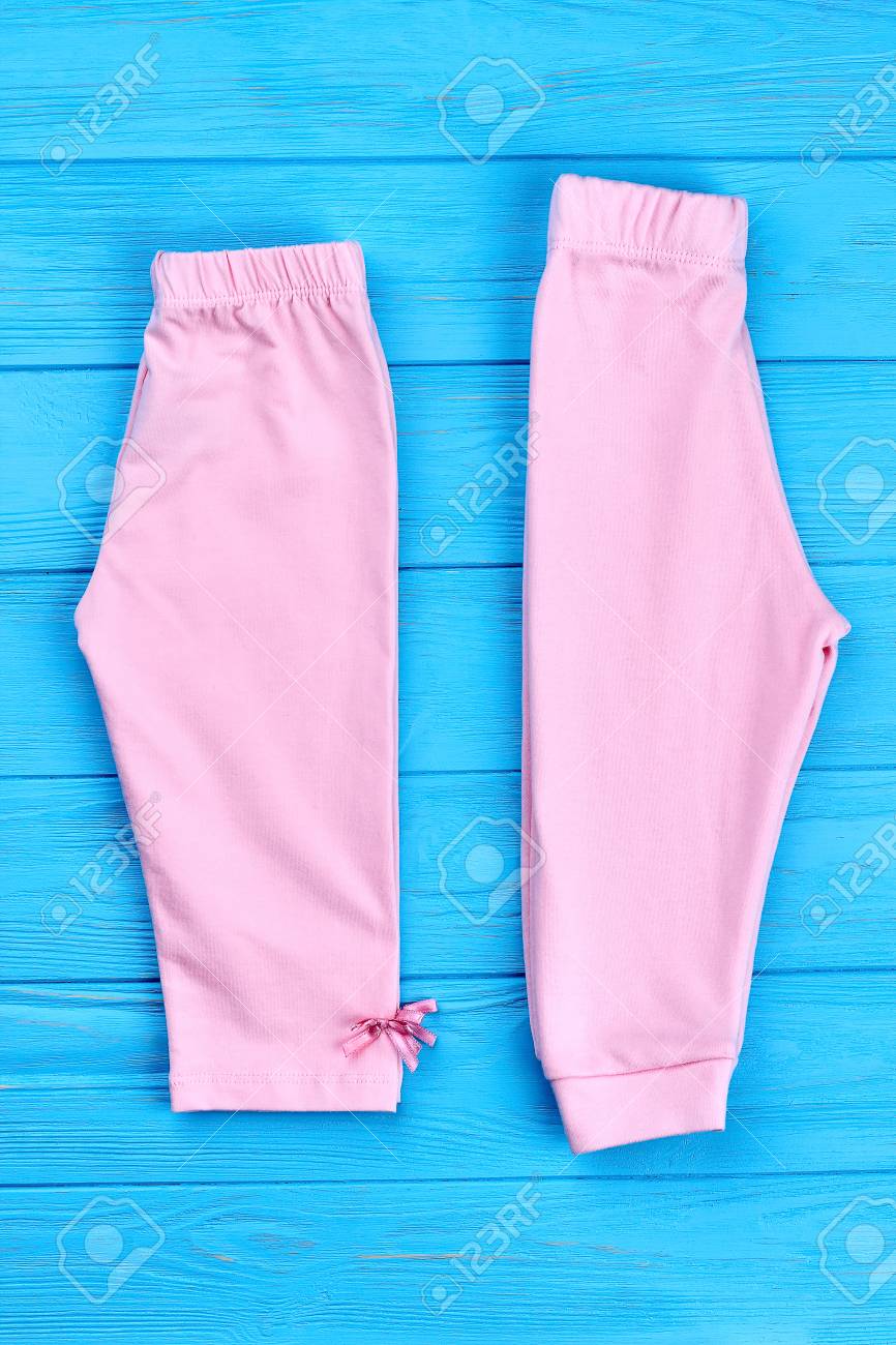 Nuevo Pantalón Doblado Para Niñas Pequeñas. Bebé Hermoso Niña Capri Y Pantalones Sobre Fondo De Madera Coloreada. Ropa De Algodón Para Niños. Fotos, Retratos, Imágenes Y Fotografía De Archivo De