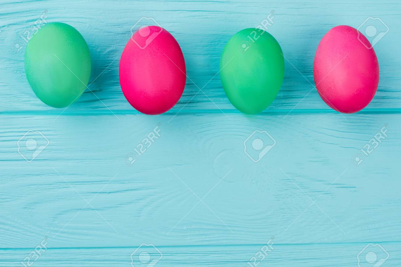 カラフルなイースターエッグの列 コピースペースと青い背景に緑と赤のイースターエッグの行 イースターの挨拶のためのアイデア の写真素材 画像素材 Image