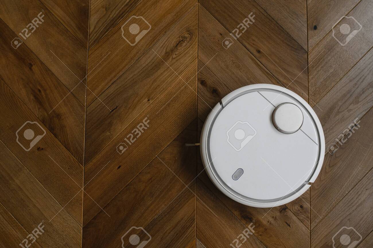 Robotic Vacuum Cleaner On Laminate Wood Floor In Bedroom Stock