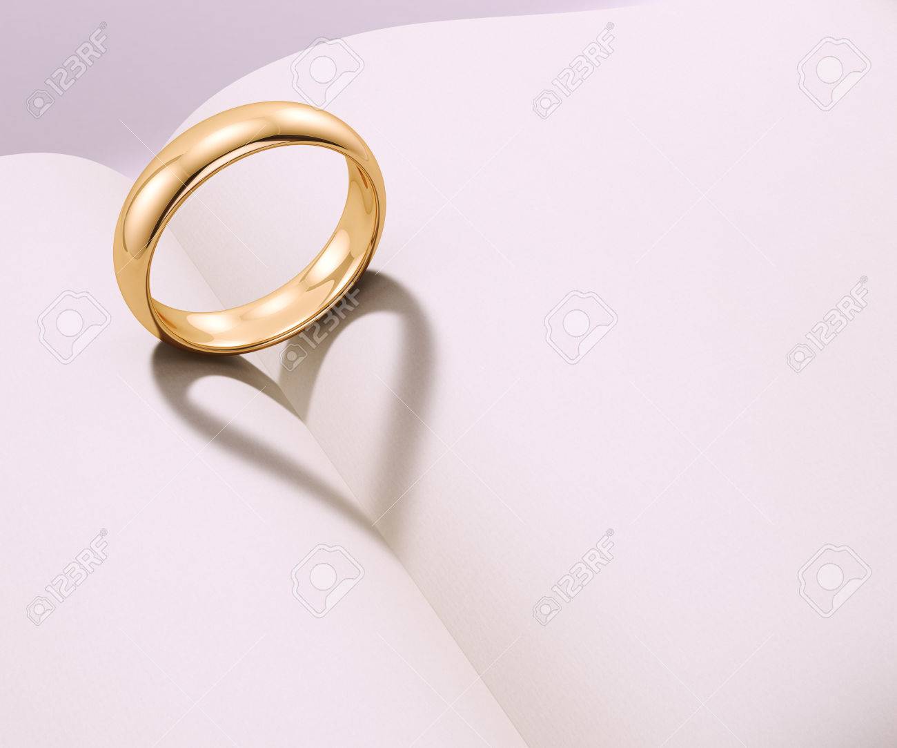 Wedding ring casting heart shaped shadow over a blank book - 51112440 Wedding ring casting heart shaped shadow over a blank book - 51112440