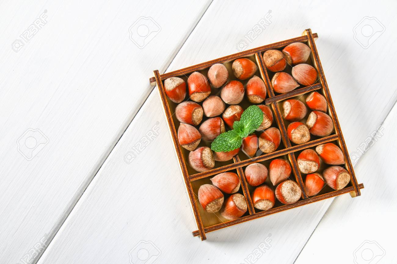 Walnut Hazelnuts In A Square Wooden Box With Dividers On White