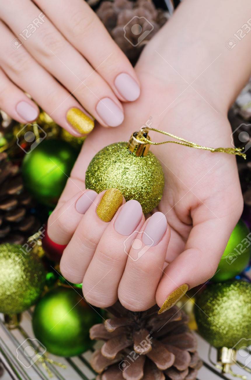 ベージュの美しい女性の手はネイル デザインです。黄金のアクセントでクリスマスのマニキュア。