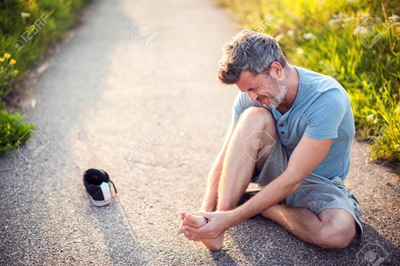 Healthcare, Medicine And People Concept. Unhappy Man Sitting On The Ground  Suffering From Pain In Feet Фотография, картинки, изображения и  сток-фотография без роялти. Image 109147155