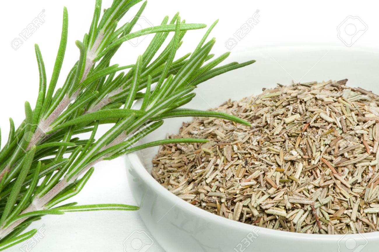 sprig fresh rosemary and a bowl with dried rosemary stock photo