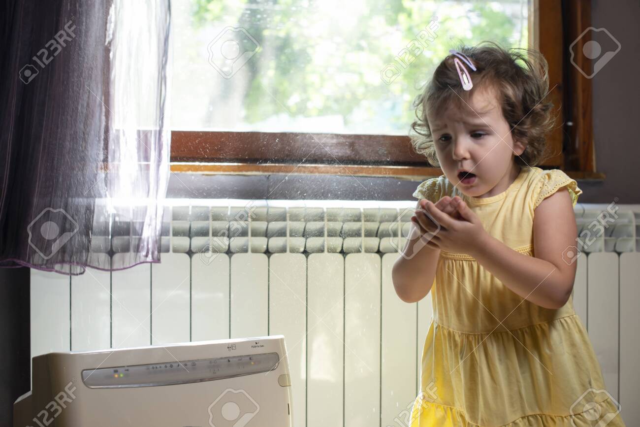 Little girl in a dusty room. Air purifier and coughing kid. Dust in the air. Allergy concept. - 128382800 Little girl in a dusty room. Air purifier and coughing kid. Dust in the air. Allergy concept. - 128382800