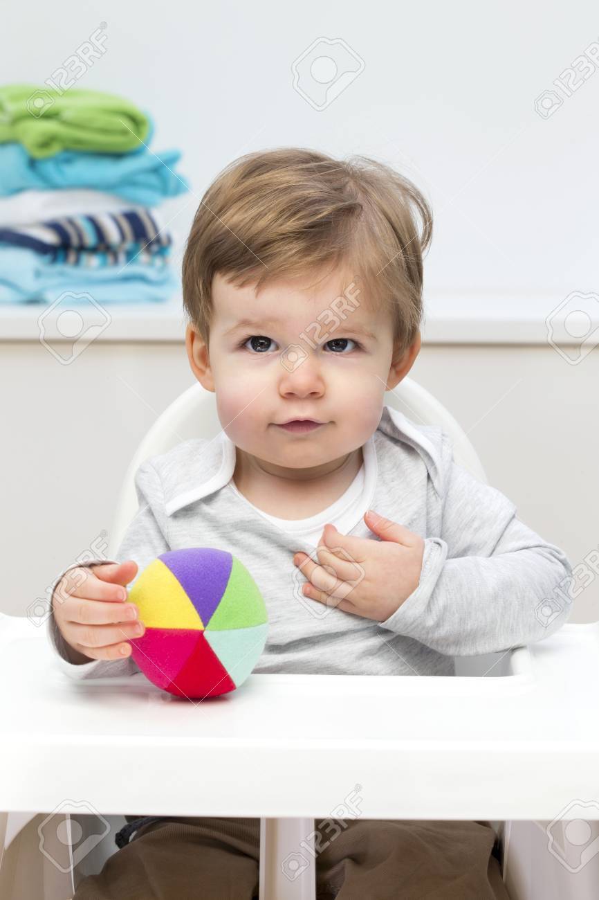 niño en una silla sentado y una pelota debajo niño en una silla sentado y una pelota debajo