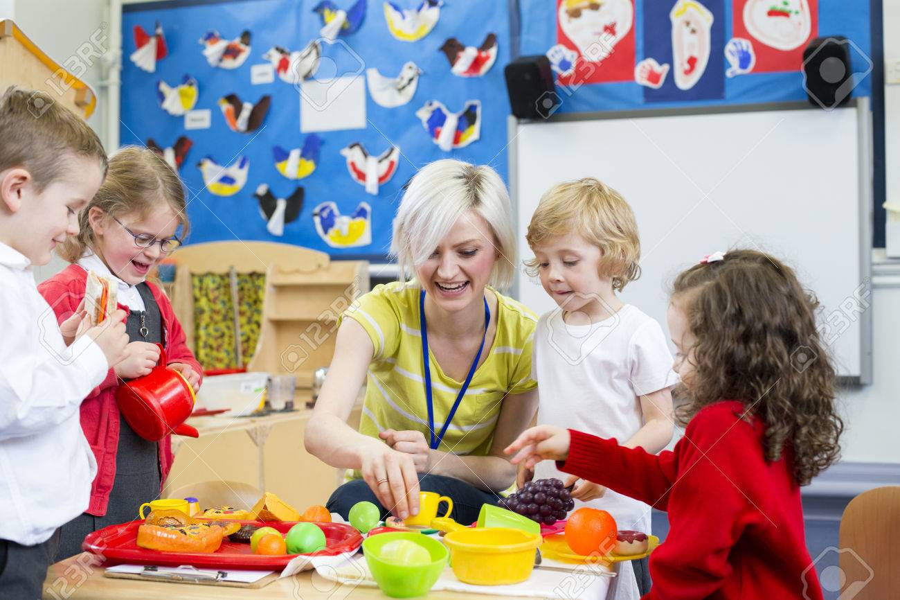 Nursery teacher playing kitchen roleplay with her students in the classroom. - 60255960 Nursery teacher playing kitchen roleplay with her students in the classroom. - 60255960
