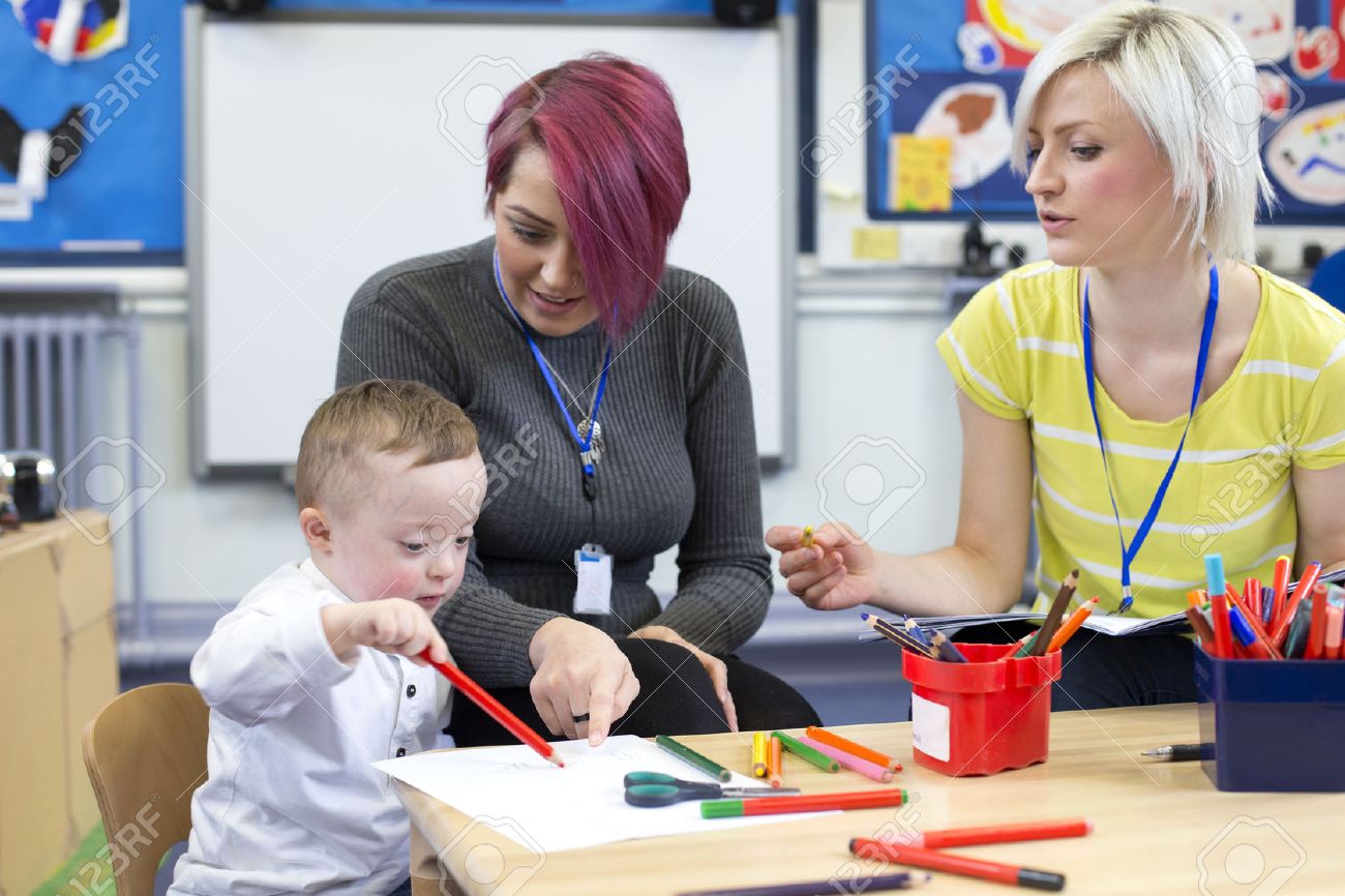 Nursery teacher sitting with a parent and her Down Syndrome son in the classroom. they are discussing the little boys progress. - 60255962 Nursery teacher sitting with a parent and her Down Syndrome son in the classroom. they are discussing the little boys progress. - 60255962