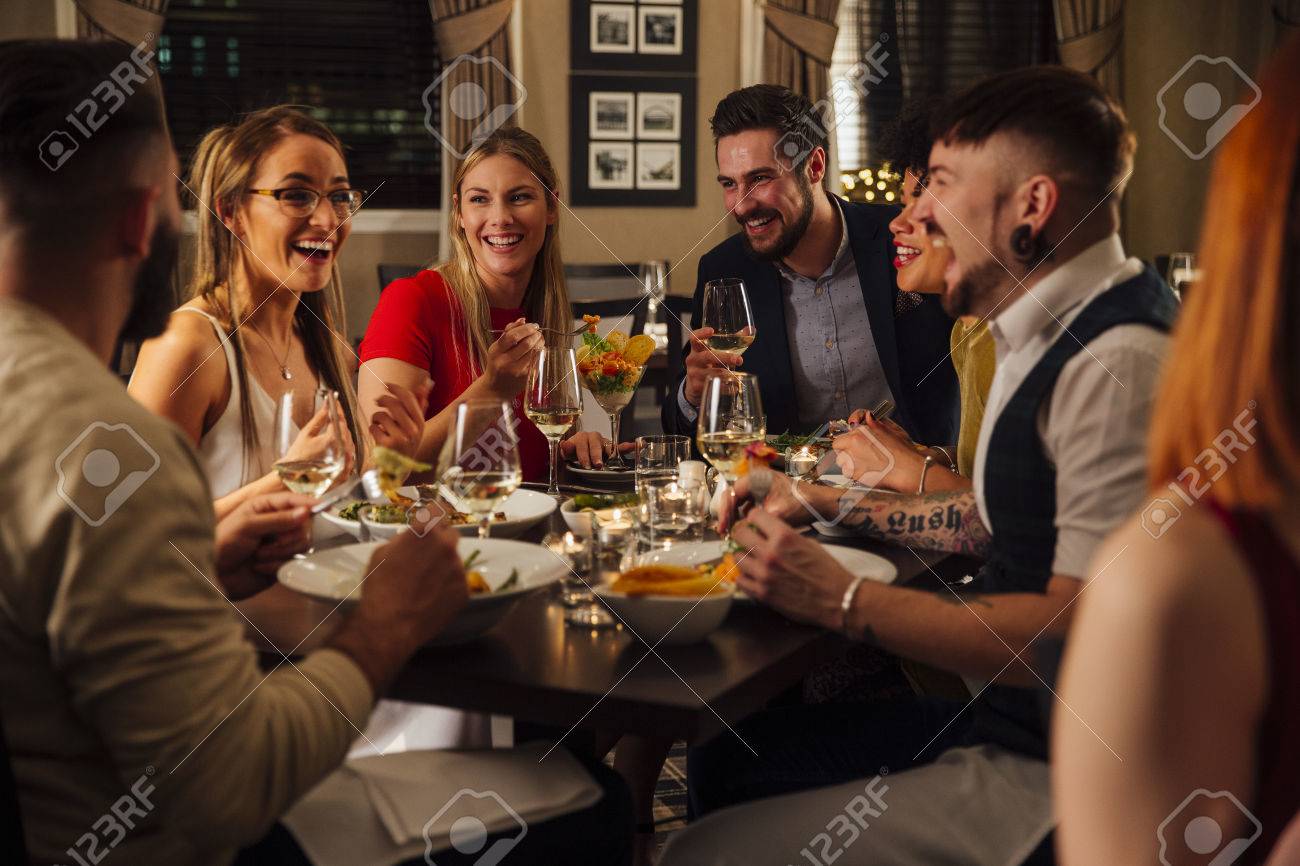 Group of friends are enjoying a meal together. They are talking and laughing while eating their starters and drinking champagne. - 75044752 Group of friends are enjoying a meal together. They are talking and laughing while eating their starters and drinking champagne. - 75044752